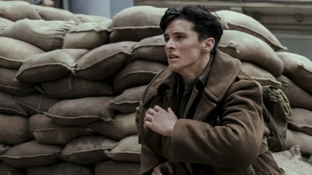 En ung soldat, en del av rollistan i Dunkirk, gömmer sig bakom sandsäckar.
