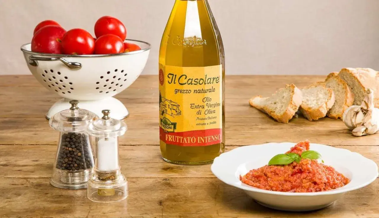 Un plat de pappa al pomodoro, garni de basilic, avec des tomates fraîches, du pain, de l'huile d'olive et des moulins à poivre et sel.