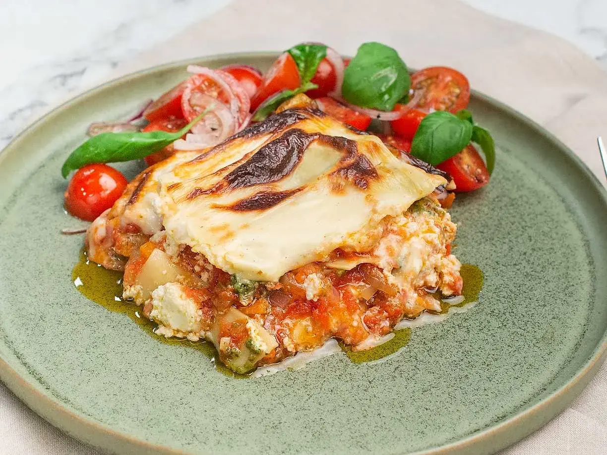 En bit krämig pesto lasagne med en fräsch tomatsallad.