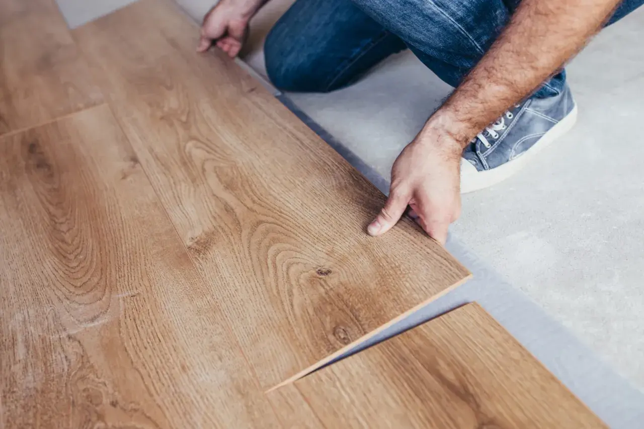 Installazione di un nuovo pavimento in laminare parquet. Le assi in legno chiaro vengono posate con cura.