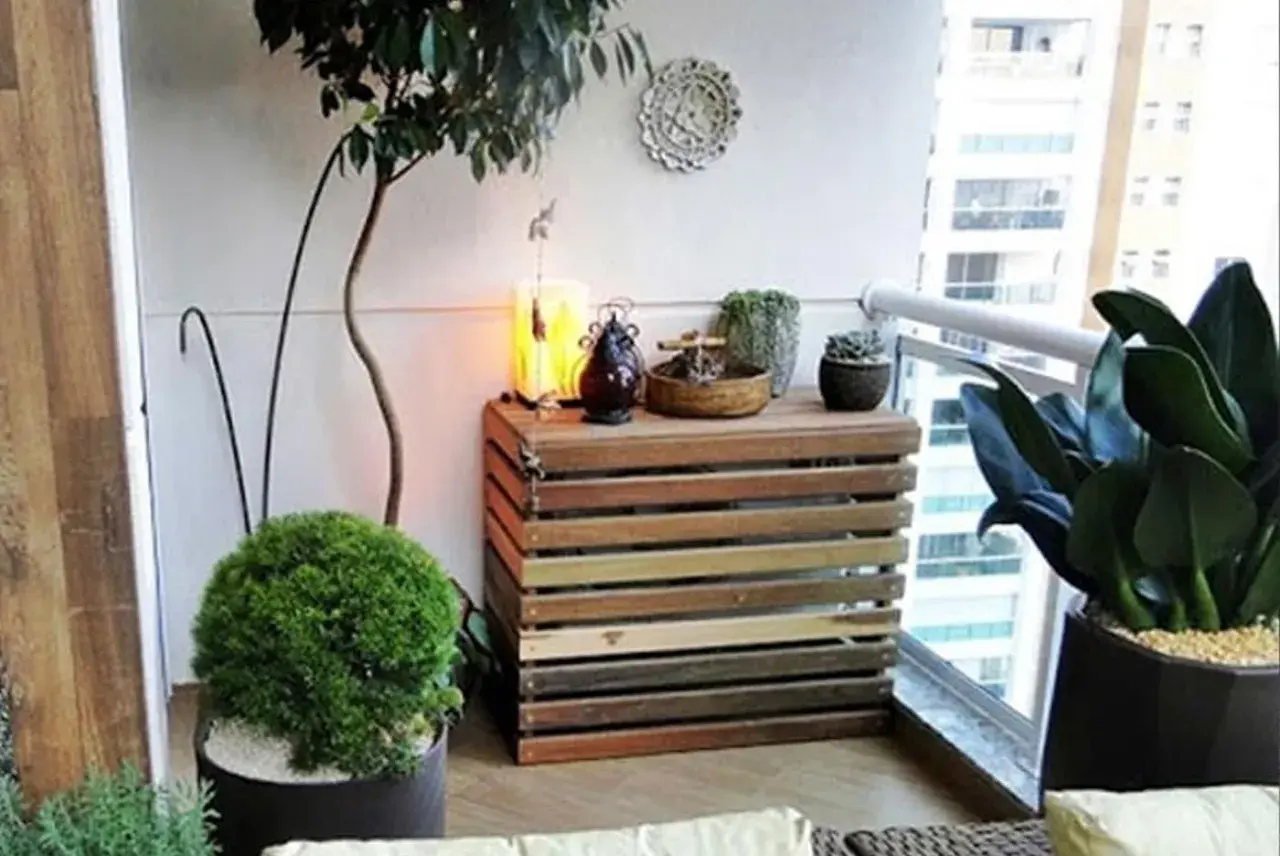 Mueble de madera para tapar unidad exterior aerotermia, decorado con plantas y objetos.