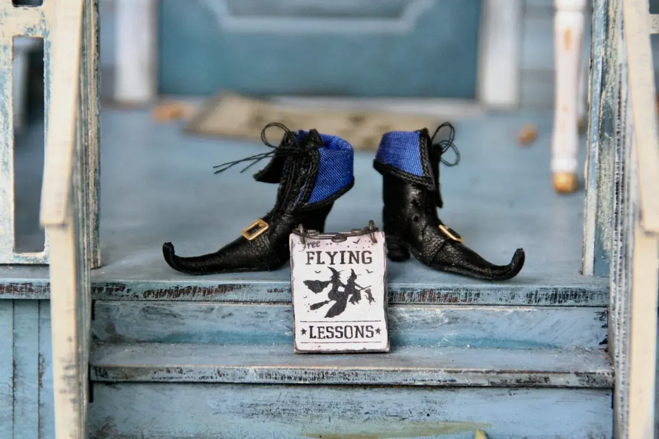Stivaletti da strega neri con un cartello "Free Flying Lessons" per le parole di Halloween.