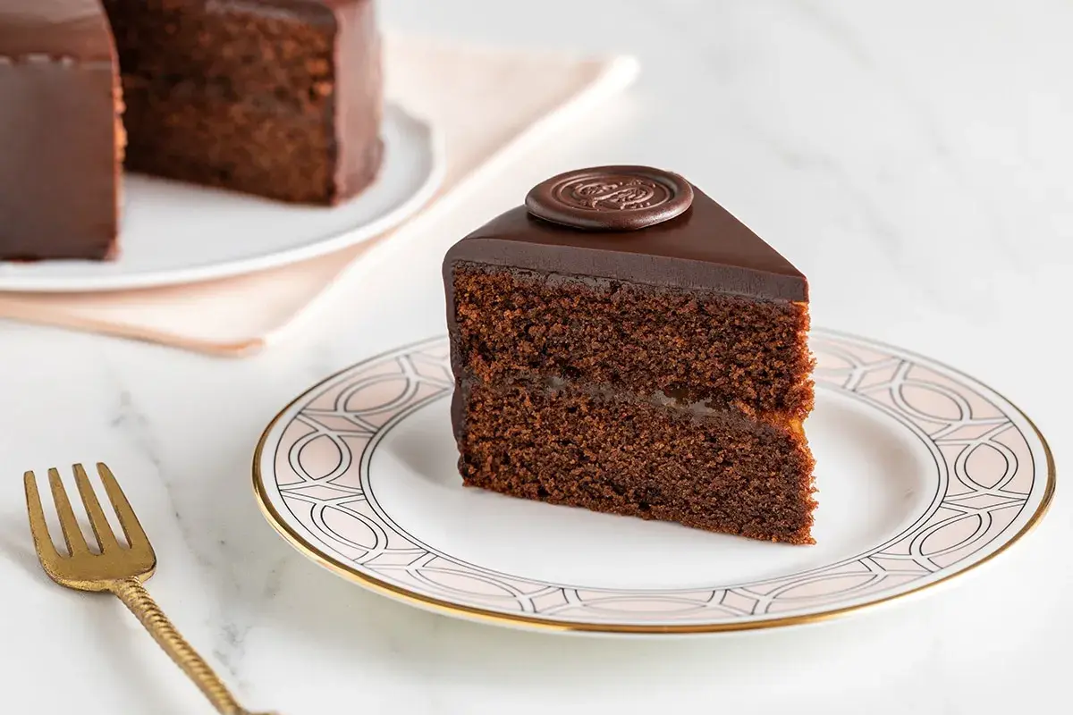 Una fetta di torta Sacher, con la sua glassa lucida e il ripieno di marmellata, mostra i suoi deliziosi ingredienti.