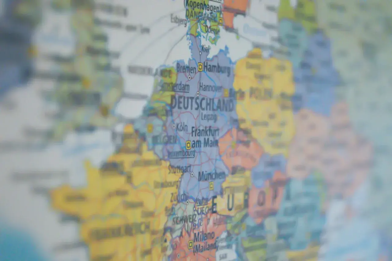 Mapa Europy z zaznaczoną DEUTSCHLAND. Widać miasta takie jak Hamburg, Frankfurt, Monachium. W tle widoczne są landy niemieckie, zakazy podróżowania w Europie.