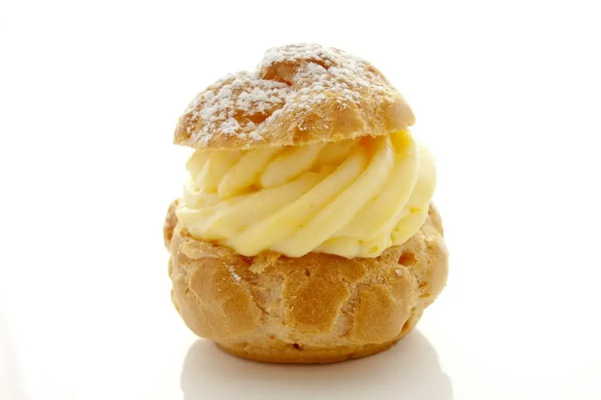 Un déliceux chou à la crème, saupoudré de sucre glace, avec une généreuse garniture de crème pâtissière onctueuse.