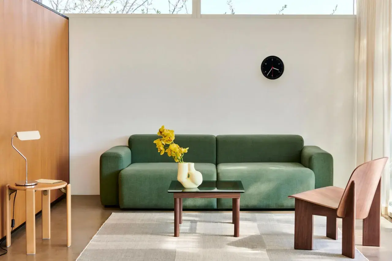 Grünes Sofa, Holzsessel und Beistelltisch im skandinavischen Einrichtungsstil. Ein moderner Wohnbereich mit minimalistischer Ästhetik.