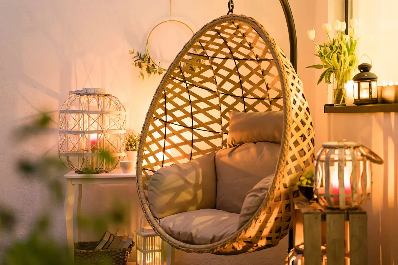Przytulny salon z fotelem wiszącym i lampionami w aranżacjach tworzącymi ciepłą atmosferę.