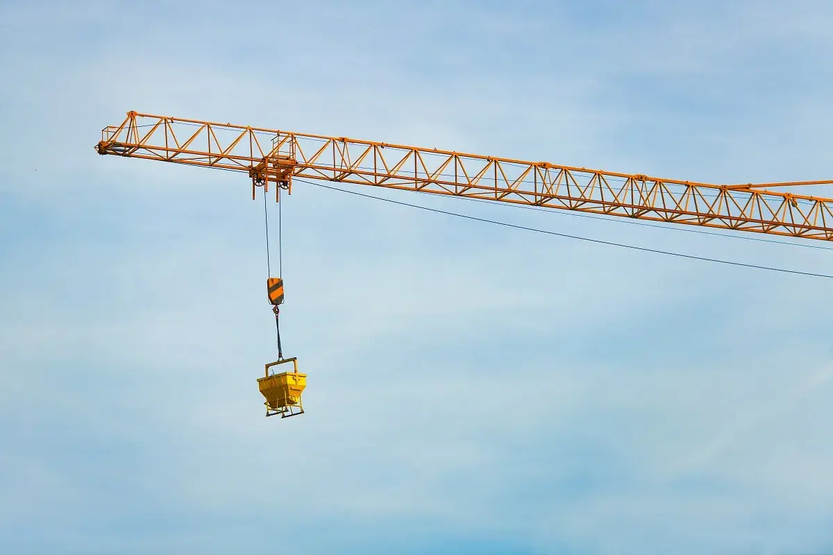 Żółty dźwig budowlany z koszem na beton. Zastanawiasz się, ile waży dźwig?