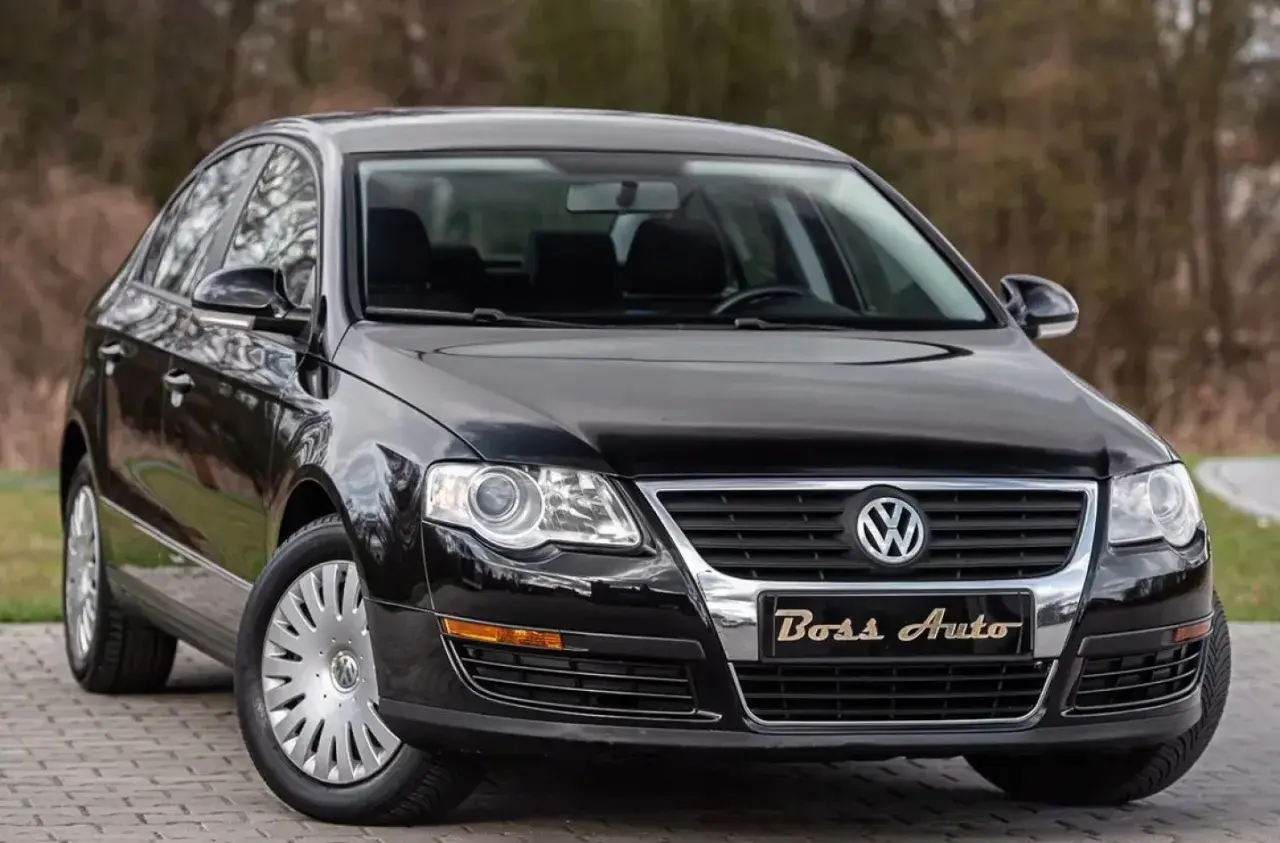Czarny Volkswagen Passat B6 na tle drzew. Elegancki, lśniący lakier i chromowane detale podkreślają jego klasę.