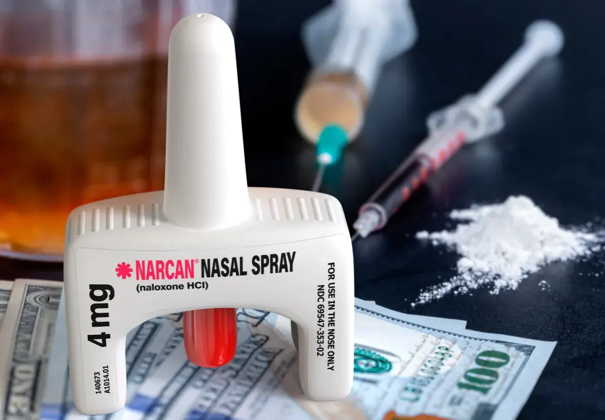 Nasalny spray nalokson, strzykawki i biały proszek na tle banknotów.