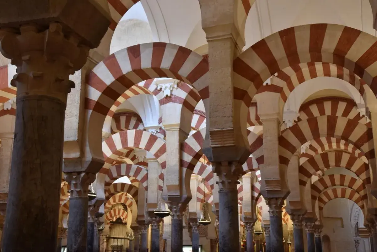 Columnas y arcos de herradura bicolores en la Mezquita de Córdoba, un ejemplo de sus diversos estilos arquitectónicos.