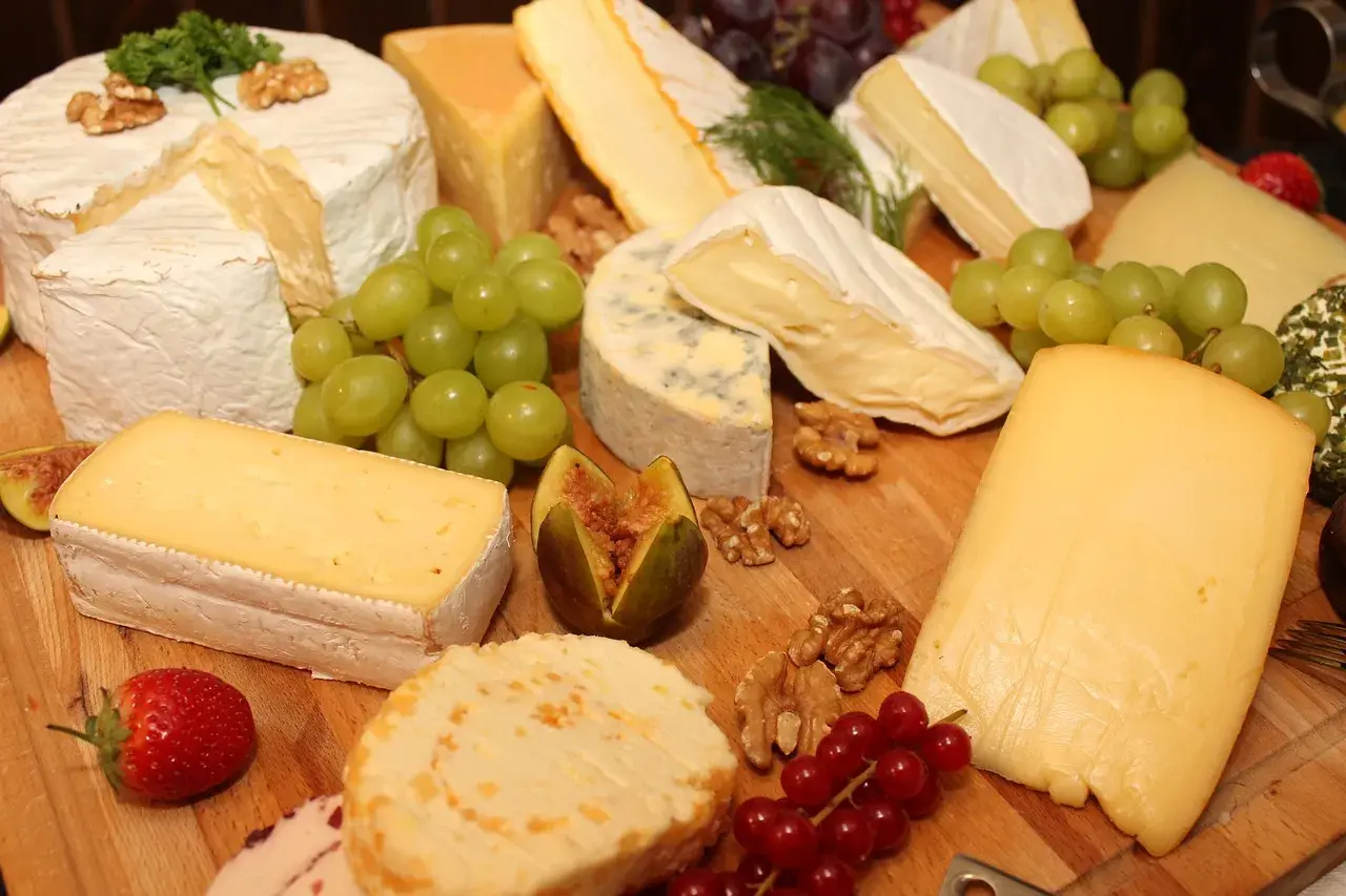 Un ricco assortimento di formaggi tipi, con uva, fichi, noci e fragole, perfetto per un aperitivo gourmet.