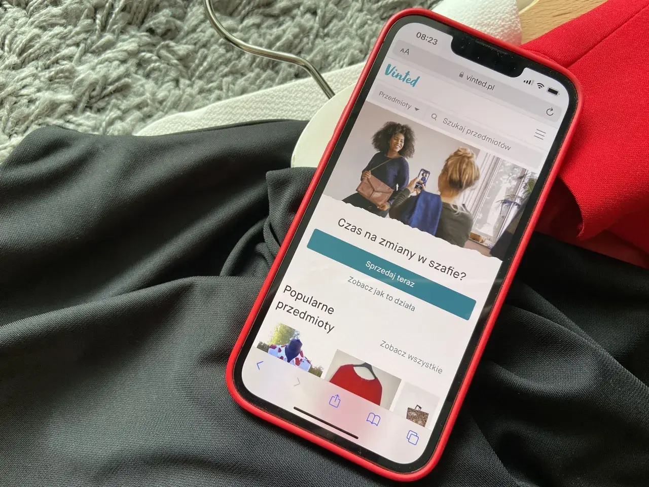 Telefon z aplikacją Vinted leży na ubraniach. Wygląda na to, że portfel Vinted nie działa, bo nie można nic sprzedać.