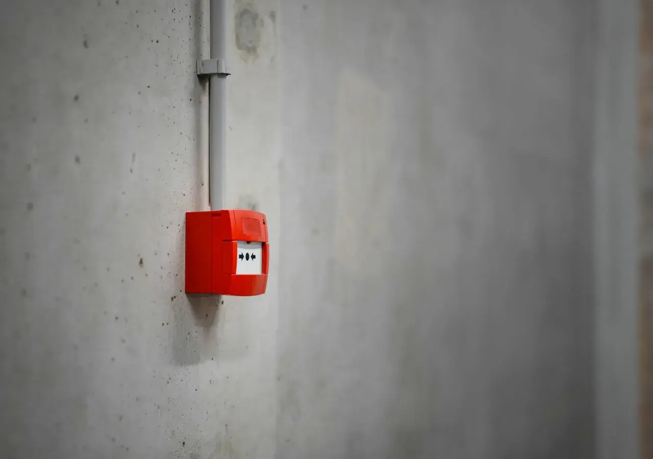 Découvrez comment fonctionne une alarme incendie : un boîtier rouge sur un mur en béton, prêt à alerter en cas de danger.