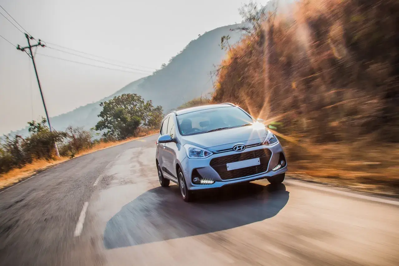 Srebrny Hyundai pędzi po krętej drodze wśród wzgórz. Czy hyundai ma ocynkowane blachy? To pytanie o jego trwałość.