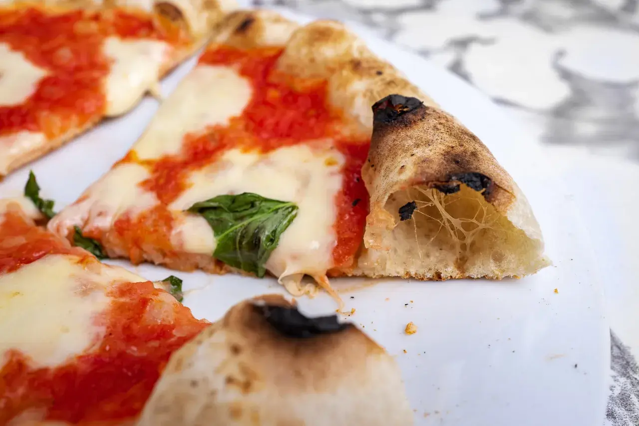 Pyszna pizza neapolitańska przepis na klasyk z pomidorami, mozzarellą i bazylią. Idealnie wypieczone ciasto z pęcherzykami powietrza.