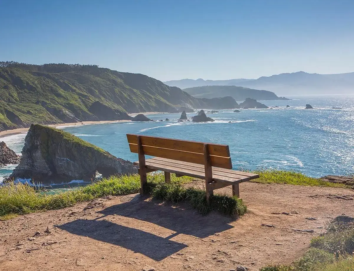 Un banco de madera invita a contemplar el mar azul y las verdes colinas. Podría ser el banco mas bonito del mundo en Vigo.