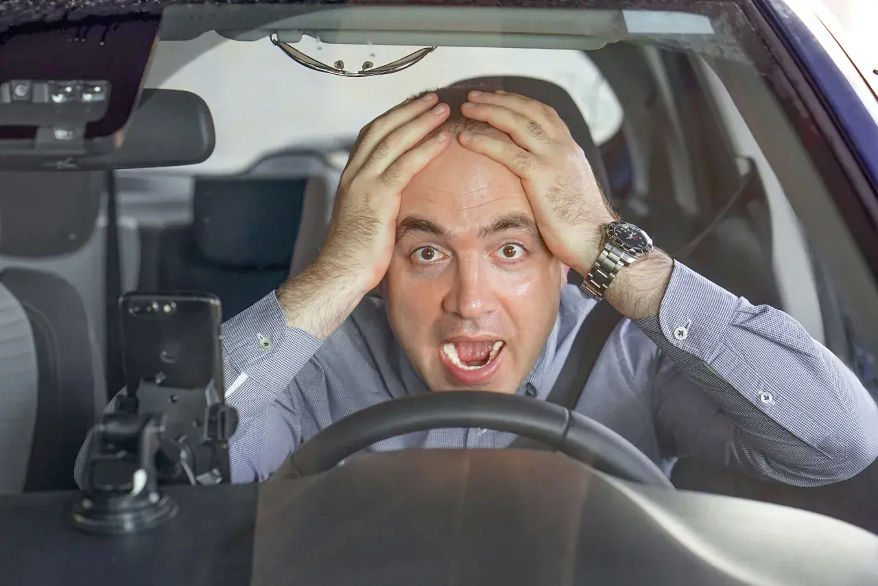 Uomo disperato al volante, mani sulla testa, con un'espressione di panico. Forse si può avere un'anomalia al differenziale.