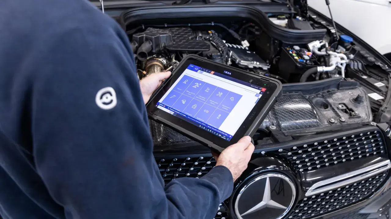 Tecnico esegue la revisione auto con tablet diagnostico, controllando i sistemi del motore.