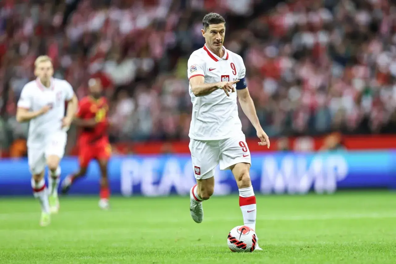Robert Lewandowski, polska fałszywa dziewiątka, prowadzi piłkę na boisku w białej koszulce z numerem 9.