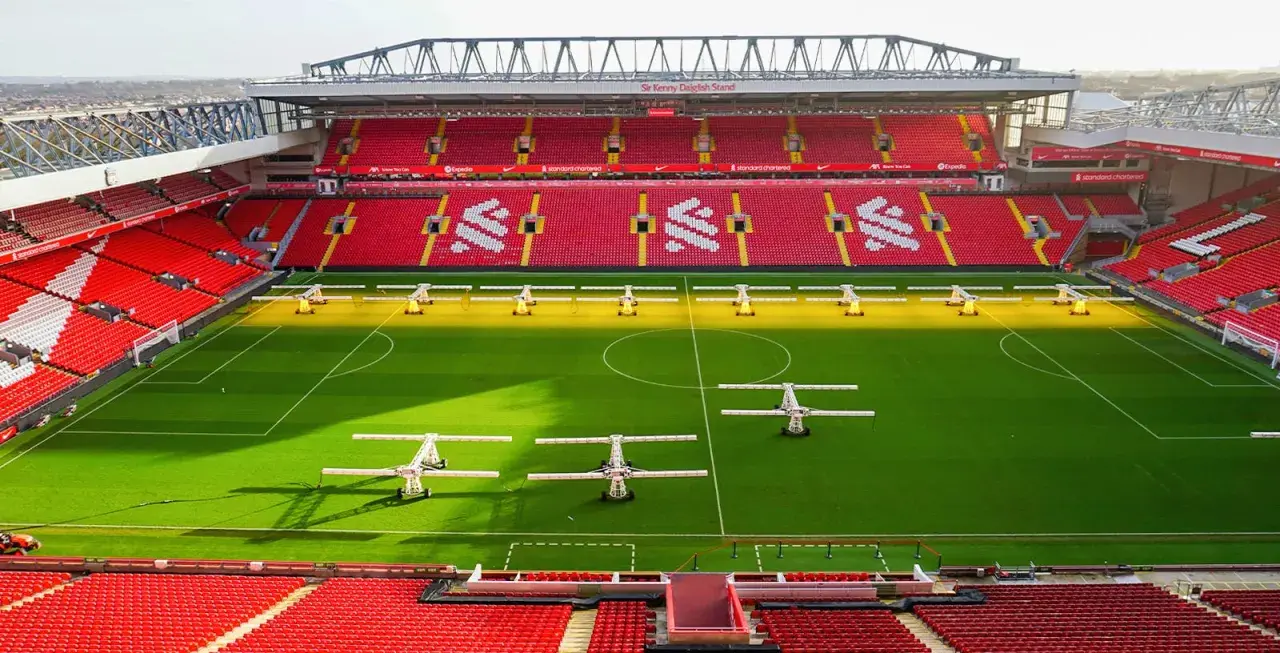 Piękny stadion w Anglii, Anfield, z czerwonymi trybunami i zieloną murawą, gotowy na kolejne emocjonujące mecze.