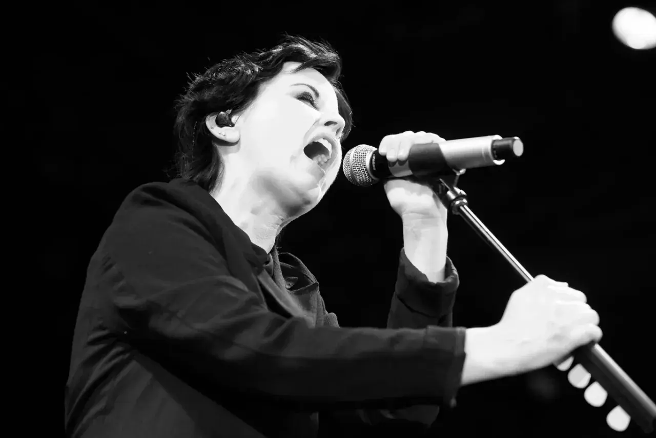 Dolores O'Riordan, jedna z członkiń The Cranberries, śpiewa do mikrofonu z pasją.