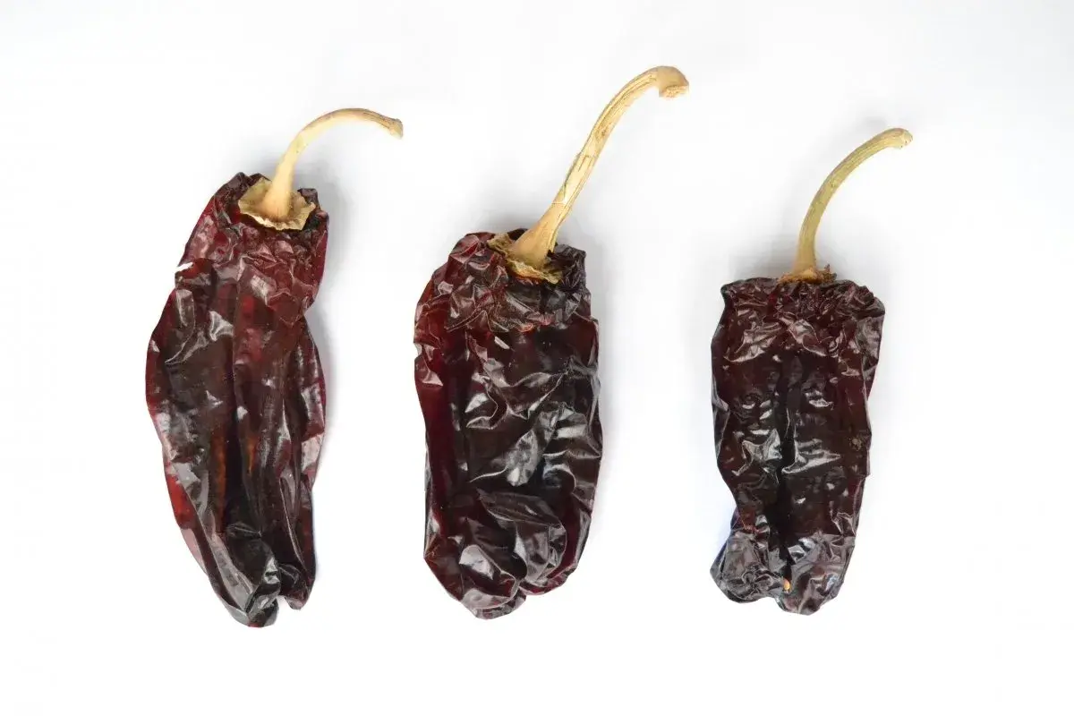 Tres pimientos choriceros secos, oscuros y arrugados, listos para dar sabor a guisos y salsas.