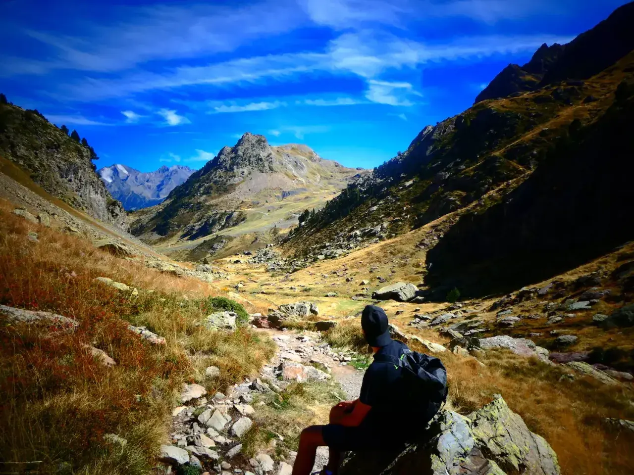 Senderista contempla la inmensidad de los montes Pirineos bajo un cielo azul intenso.