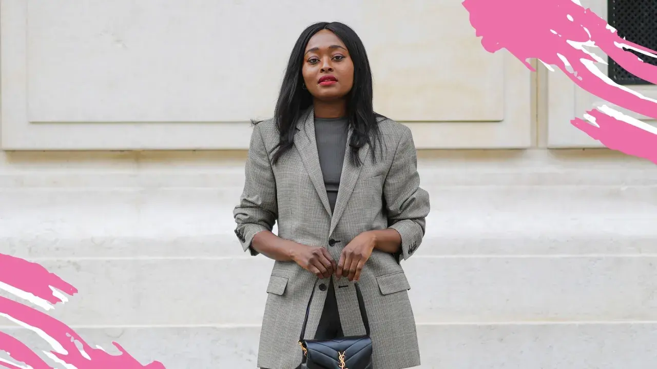 Frau in schickem Business-Outfit mit kariertem Blazer und schwarzer Handtasche, bereit für ein wichtiges Meeting.