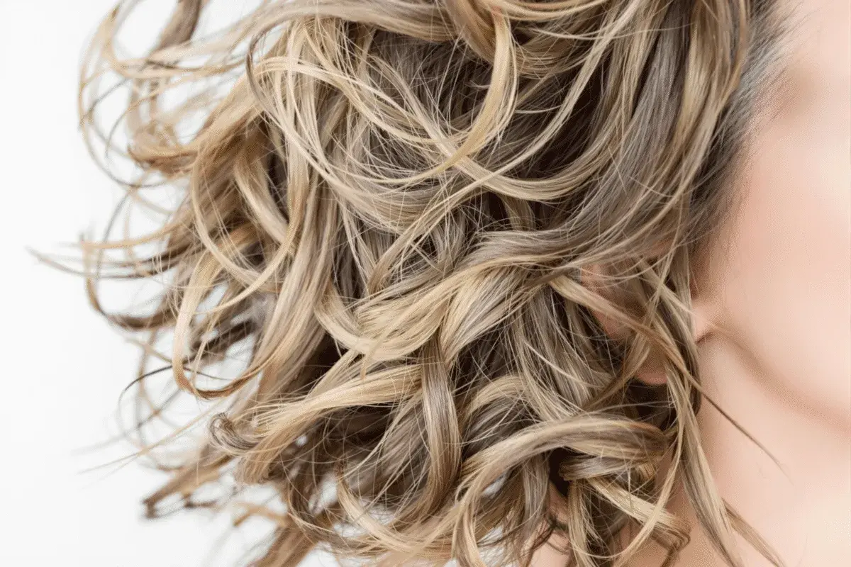 Cabello rubio ondulado y sedoso, libre de sulfatos y parabenos, con reflejos dorados.