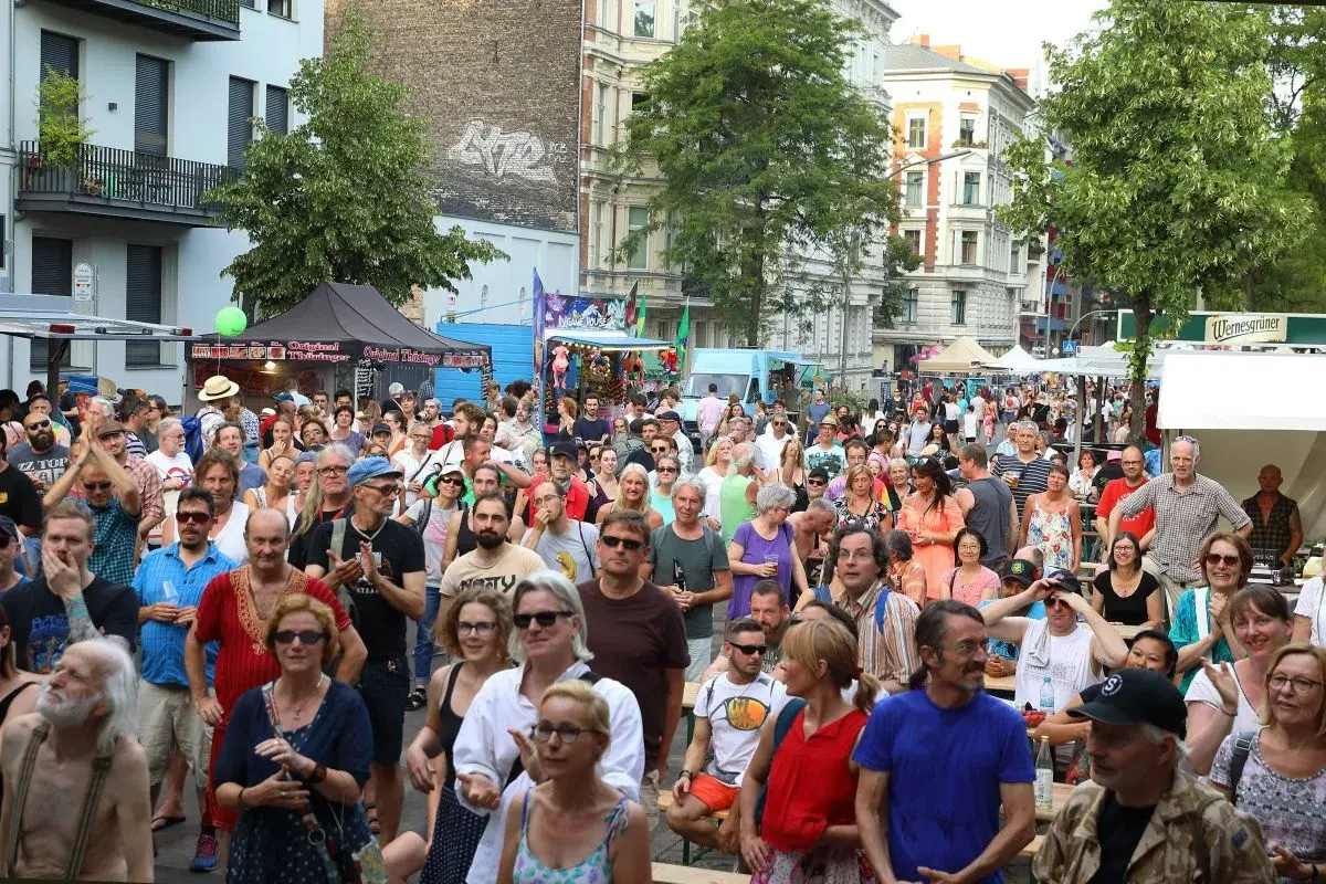 Menschenmenge feiert beim Kreuzberg Festival. Bunte Stände und ein belebtes Straßenfest mit vielen Besuchern.