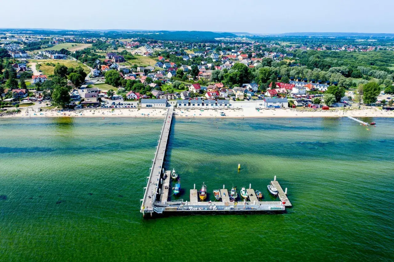 Mechelinki - warto jechać! Widok na molo, plażę i urokliwą nadmorską miejscowość.