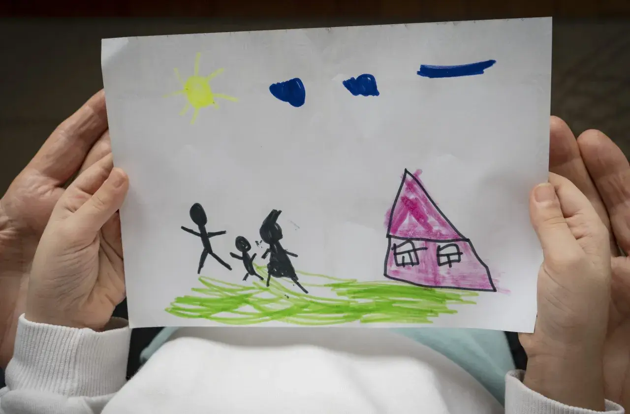 Disegni psicologia test bambini: una famiglia stilizzata cammina verso una casa rosa sotto un sole giallo e nuvole blu.