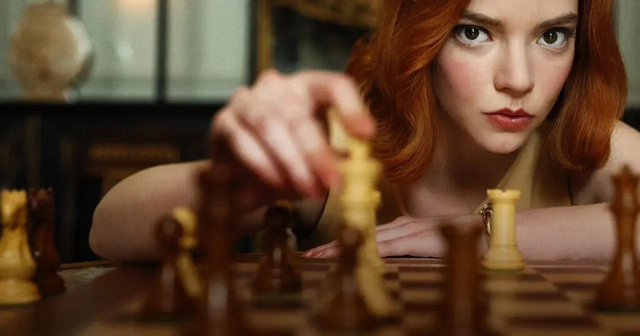 Anya Taylor-Joy jako Beth Harmon w "Gambicie Królowej" wykonuje ruch figurą na szachownicy.