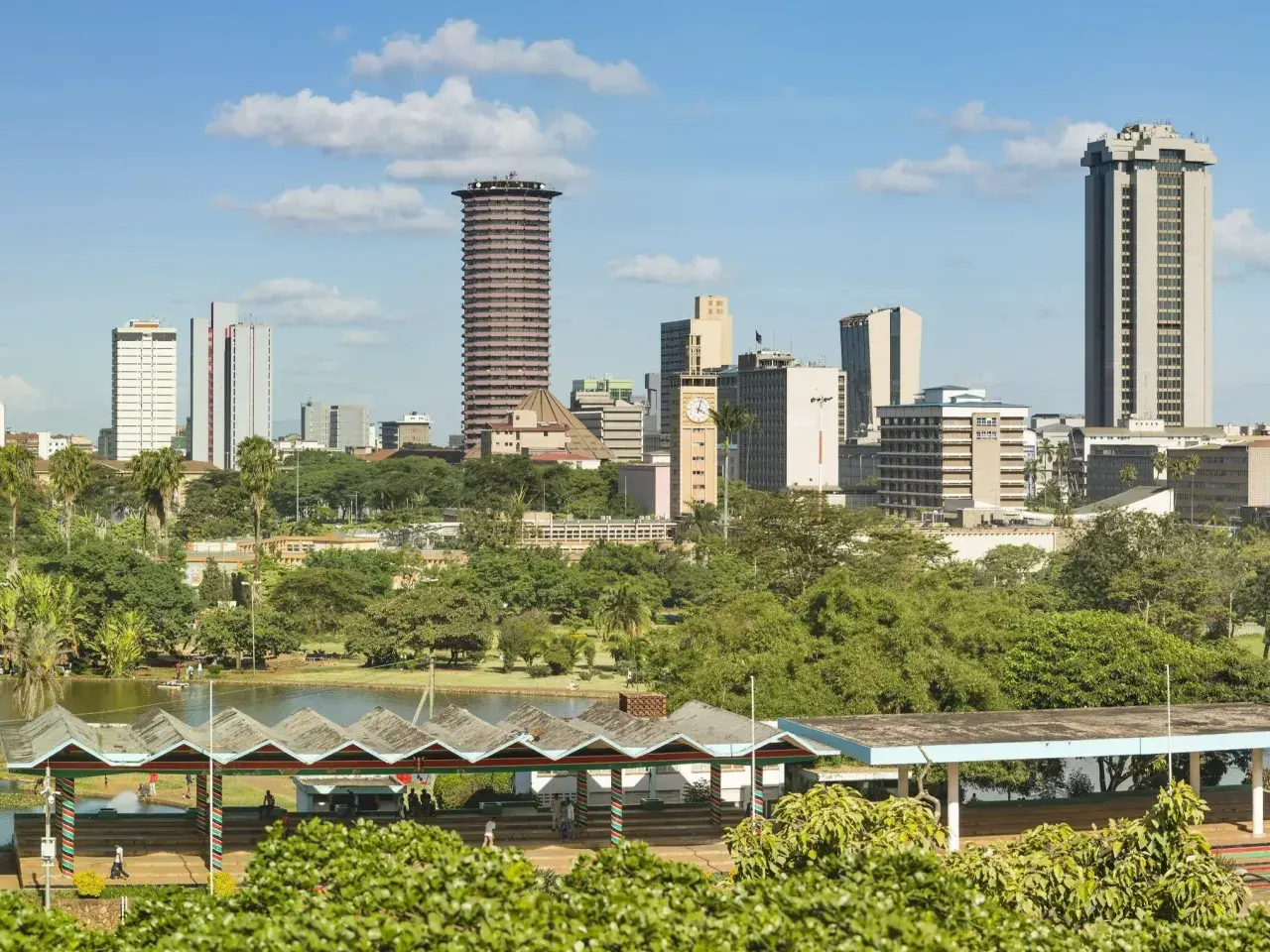 Widok na miasto z Nairobi, z wieżowcami i zielonymi drzewami. W oddali jezioro i pawilony.