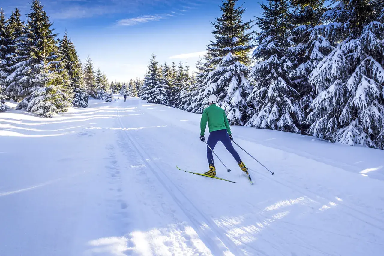 Langlauf-Spaß im verschneiten Riesengebirge, Tschechien. Ein Mann gleitet auf Skiern durch eine sonnige Winterlandschaft.