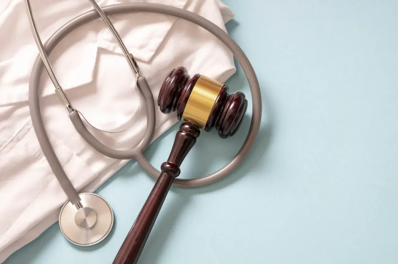 Martelletto da giudice e camice bianco con stetoscopio. Simboleggia la giustizia medica e la diagnosi sbagliata tumore.