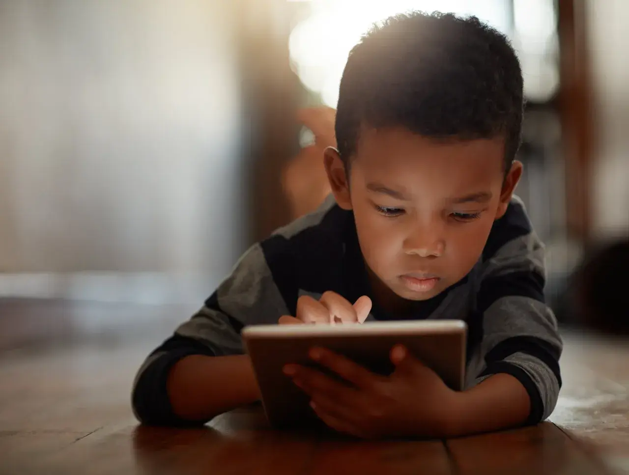 Un niño concentrado en su tablet, un ejemplo de cómo los niños introvertidos exploran mundos digitales.