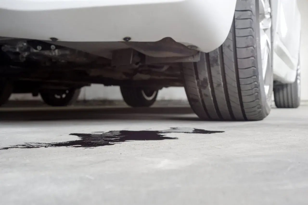 Macchia scura sul cemento sotto un'auto, probabile perdita liquido radiatore.