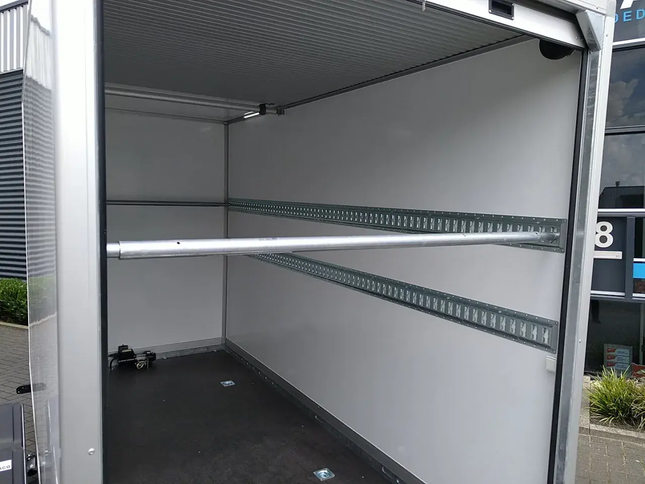 Intérieur de remorque avec rails d'arrimage et barre transversale, idéal pour le règlement chargement remorque.