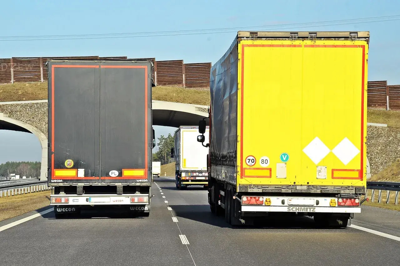 Na autostradzie jadą trzy tiry. Znak ograniczenia prędkości wskazuje, że tiry mogą jechać 70 lub 80 km/h.