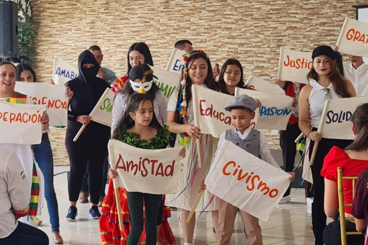 Niños sostienen pancartas con valores como "Amistad", "Civismo" y "Educación", mostrando que es la paz para niños.