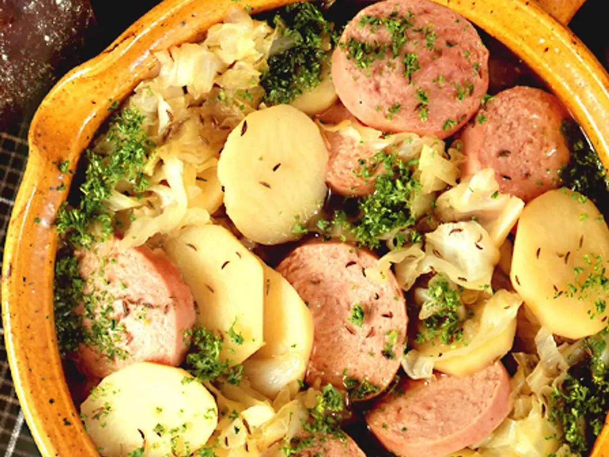 En värmande korvgryta med potatis, kål och persilja i en rustik keramikskål.