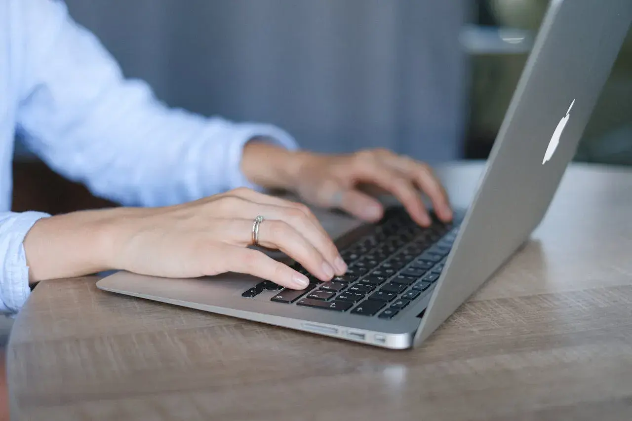 Mani su tastiera di un laptop, con anello nuziale. Lavoro da remoto per ottenere myecm crediti.