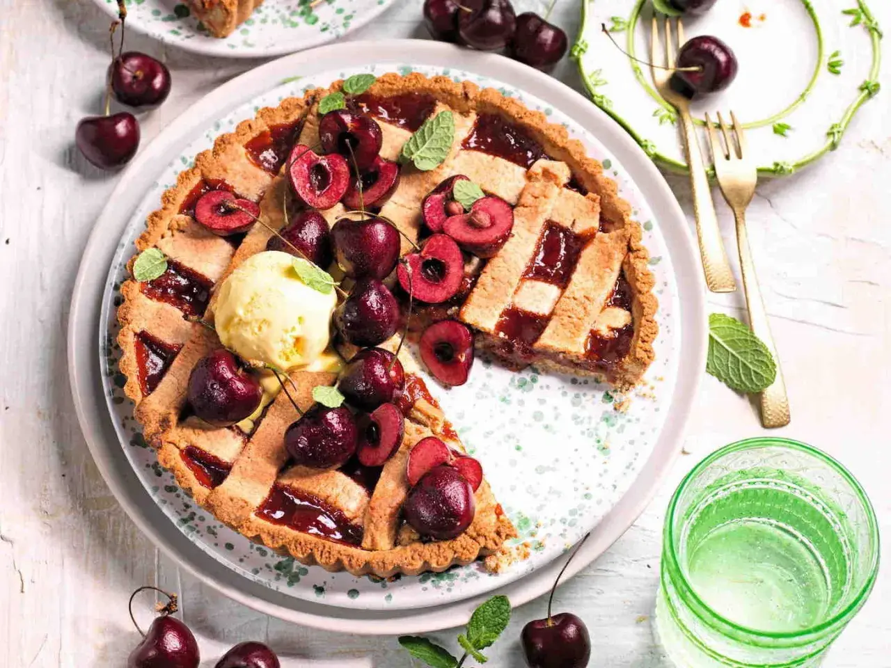 Una deliziosa crostata di ciliegie, guarnita con ciliegie fresche, gelato alla vaniglia e foglioline di menta. Perfetta per un dolce estivo.
