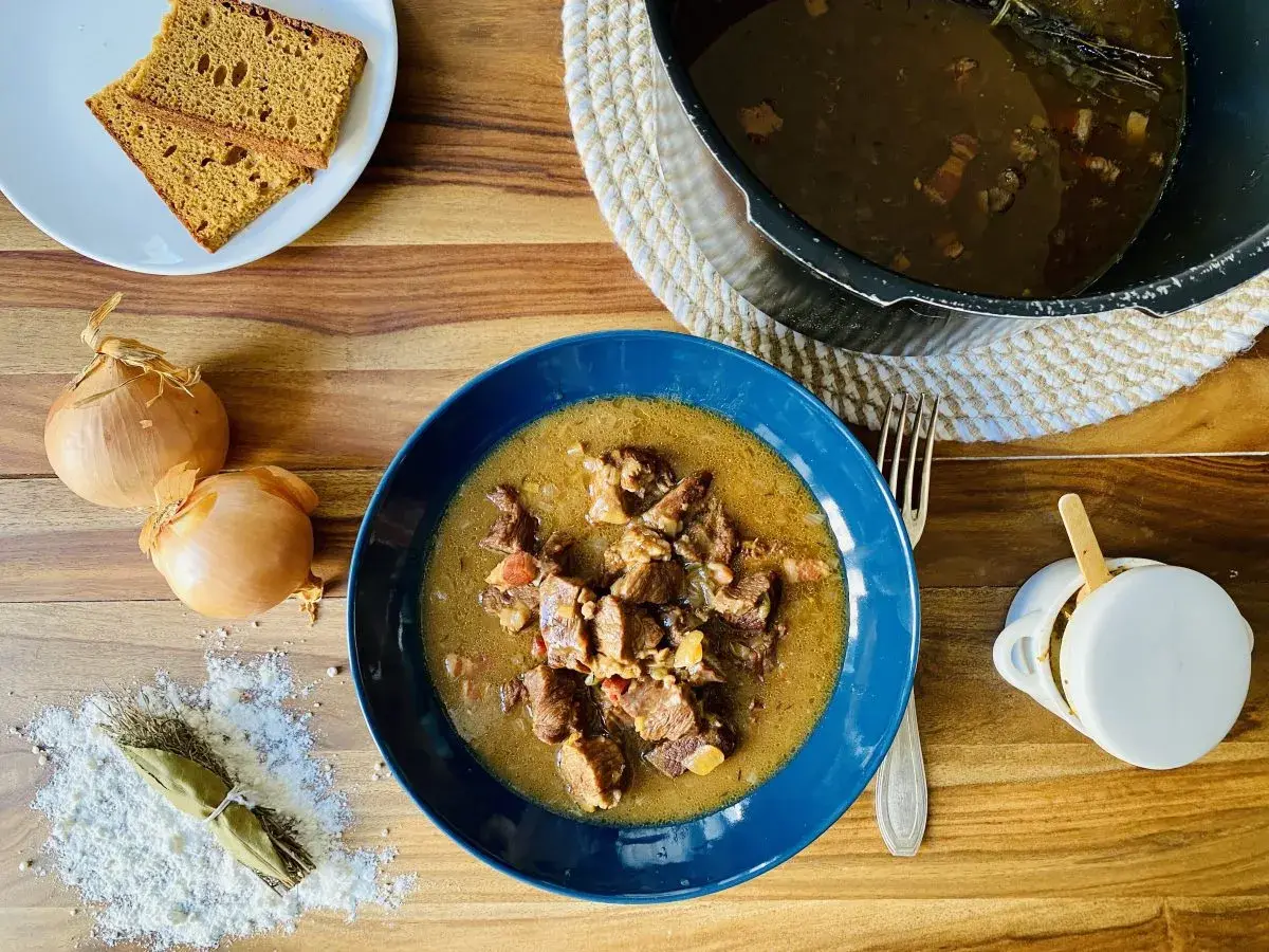 Carbonade flamande mijotée dans un Cookeo, servie dans un bol bleu avec du pain de seigle.