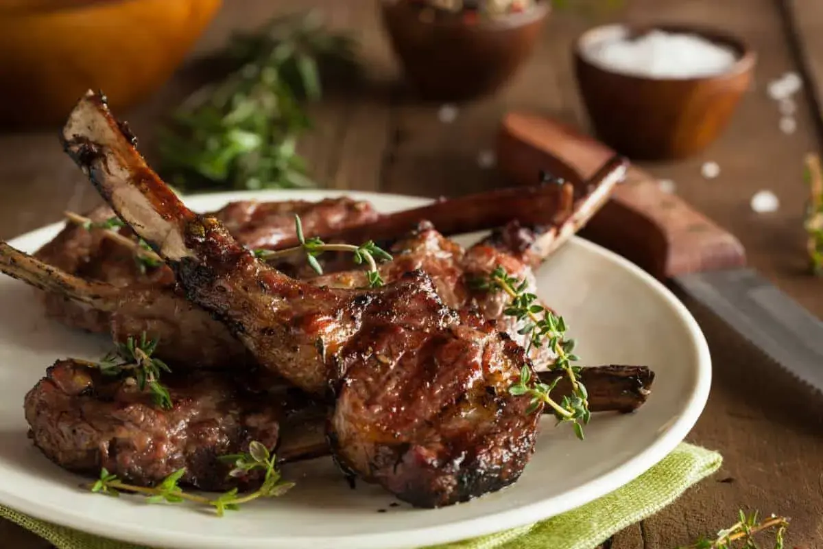 Délicieuses côtelettes d'agneau grillées, garnies de thym frais, prêtes à être dégustées.