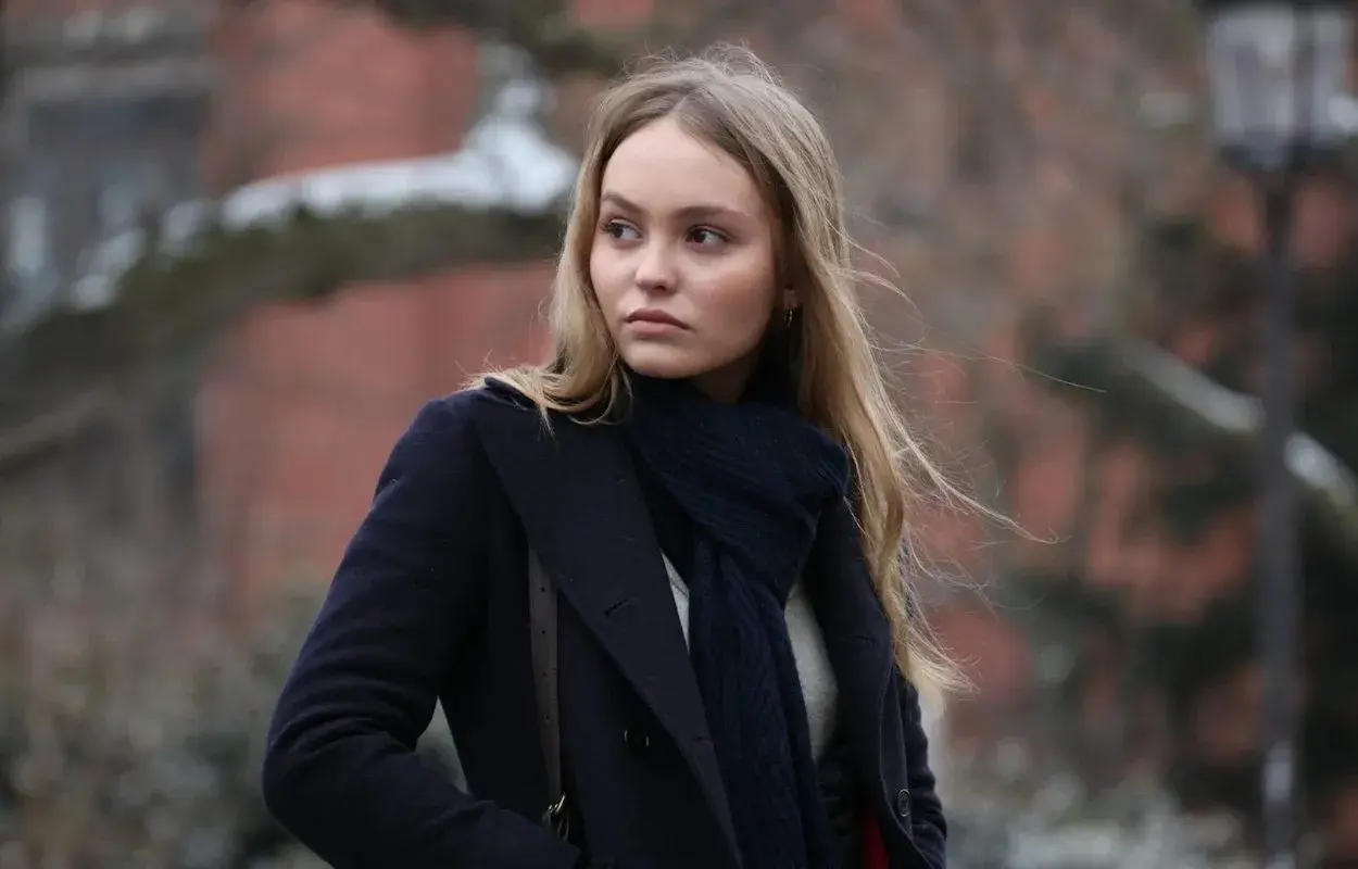 Lily-Rose Depp i en mörkblå kappa och halsduk, påminner om hennes roller i filmer.