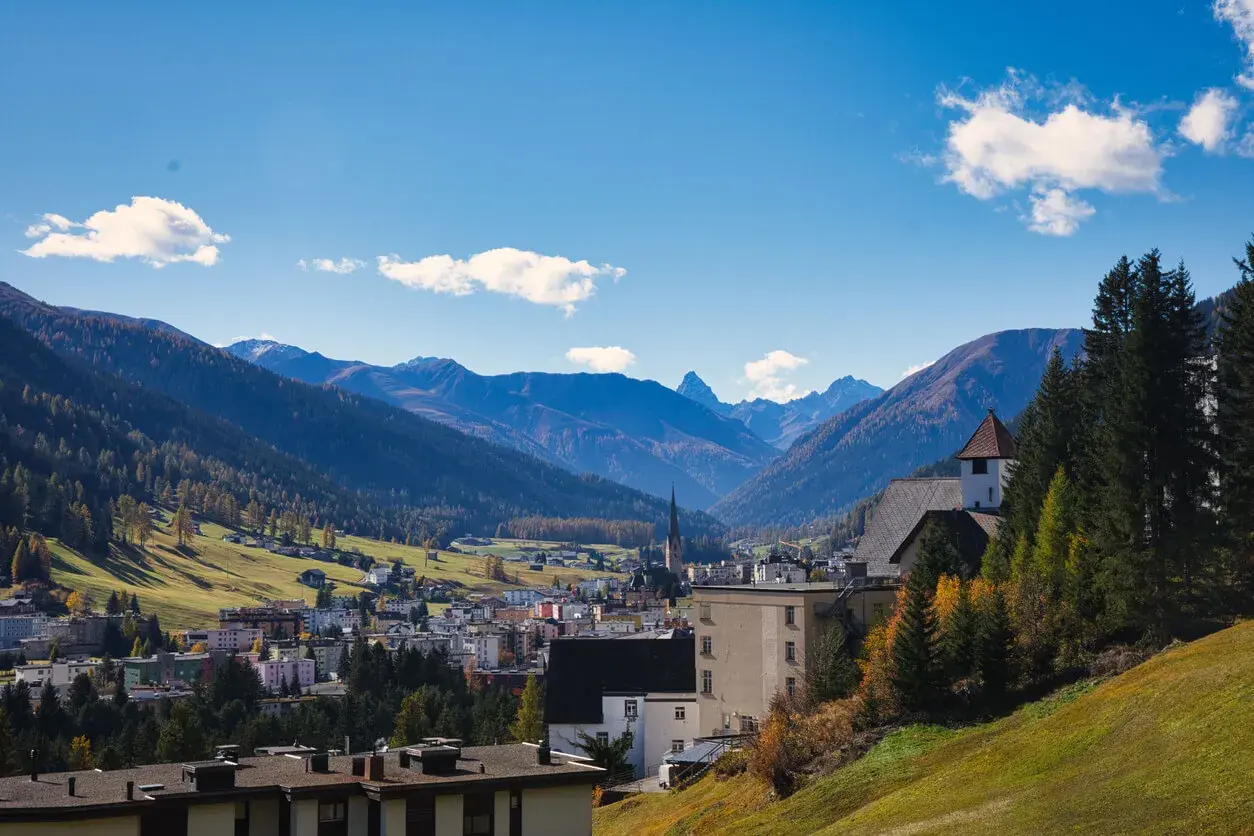 Widok na miasteczko w dolinie otoczonej górami. W oddali widać kościół z wieżą. Tak właśnie wygląda Davos.