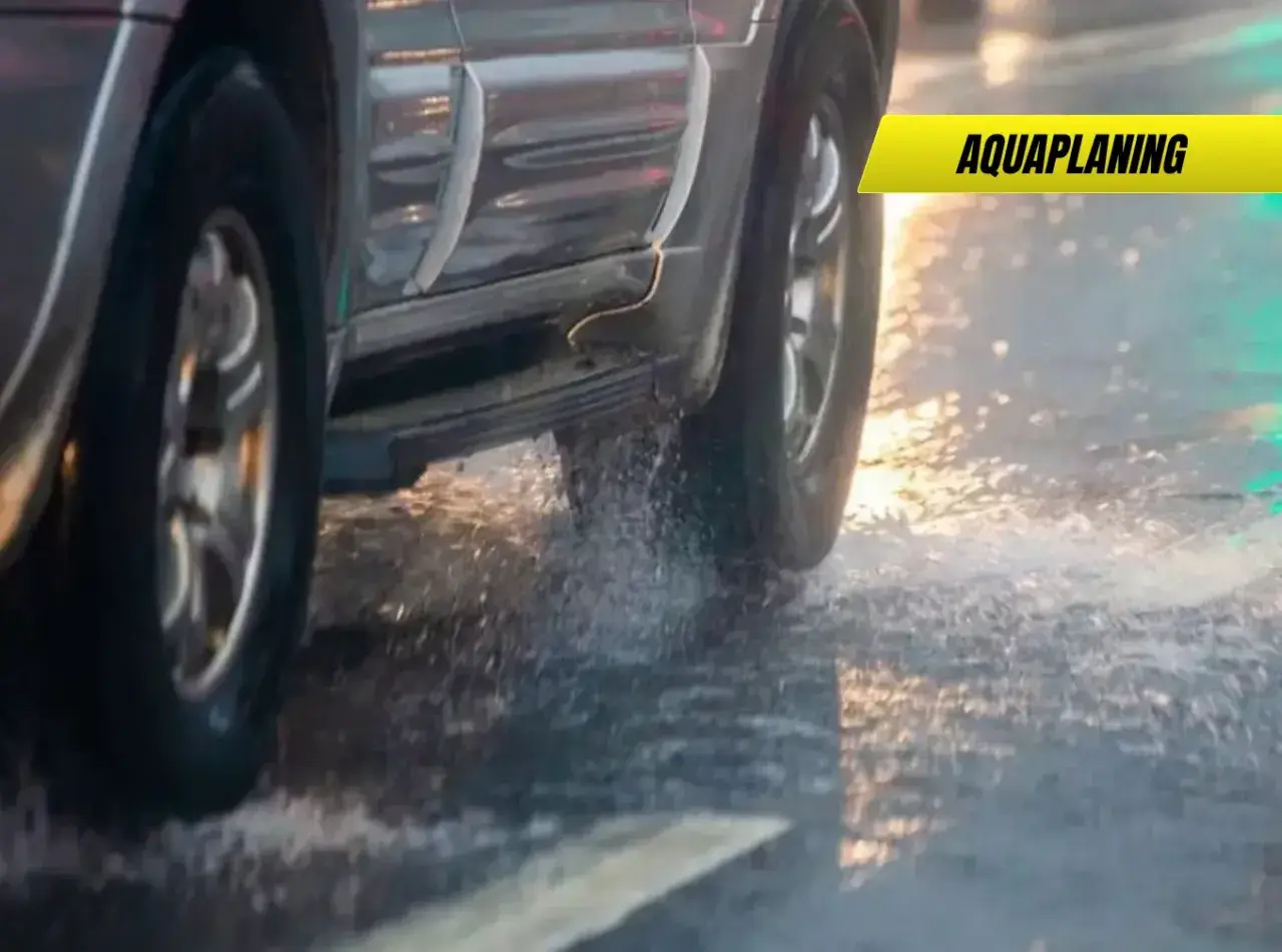 Un coche sufre aquaplaning en un día lluvioso, levantando agua al pasar.